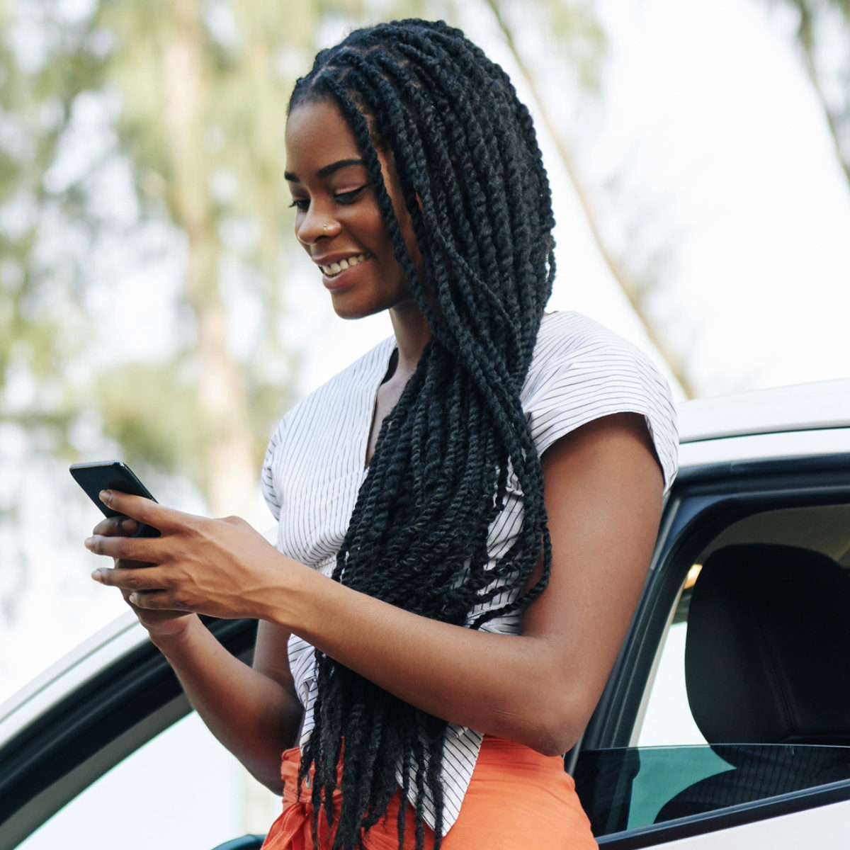 person next to vehicle using the parking app to park